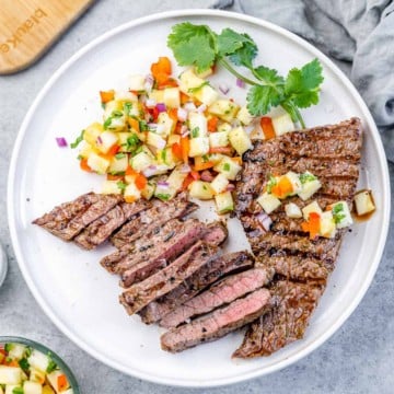 top view image of two steaks on a white plate with pineapple salsa