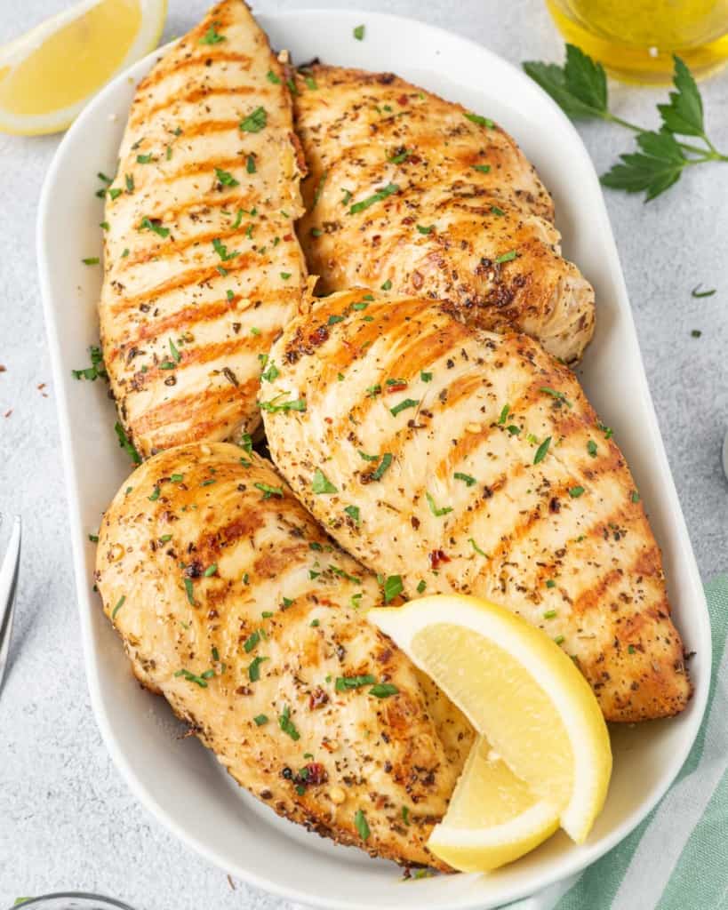 close up grilled chicken breast over a white dish