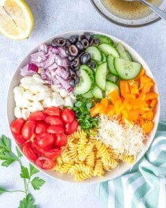 salad ingredients added to a bowl.