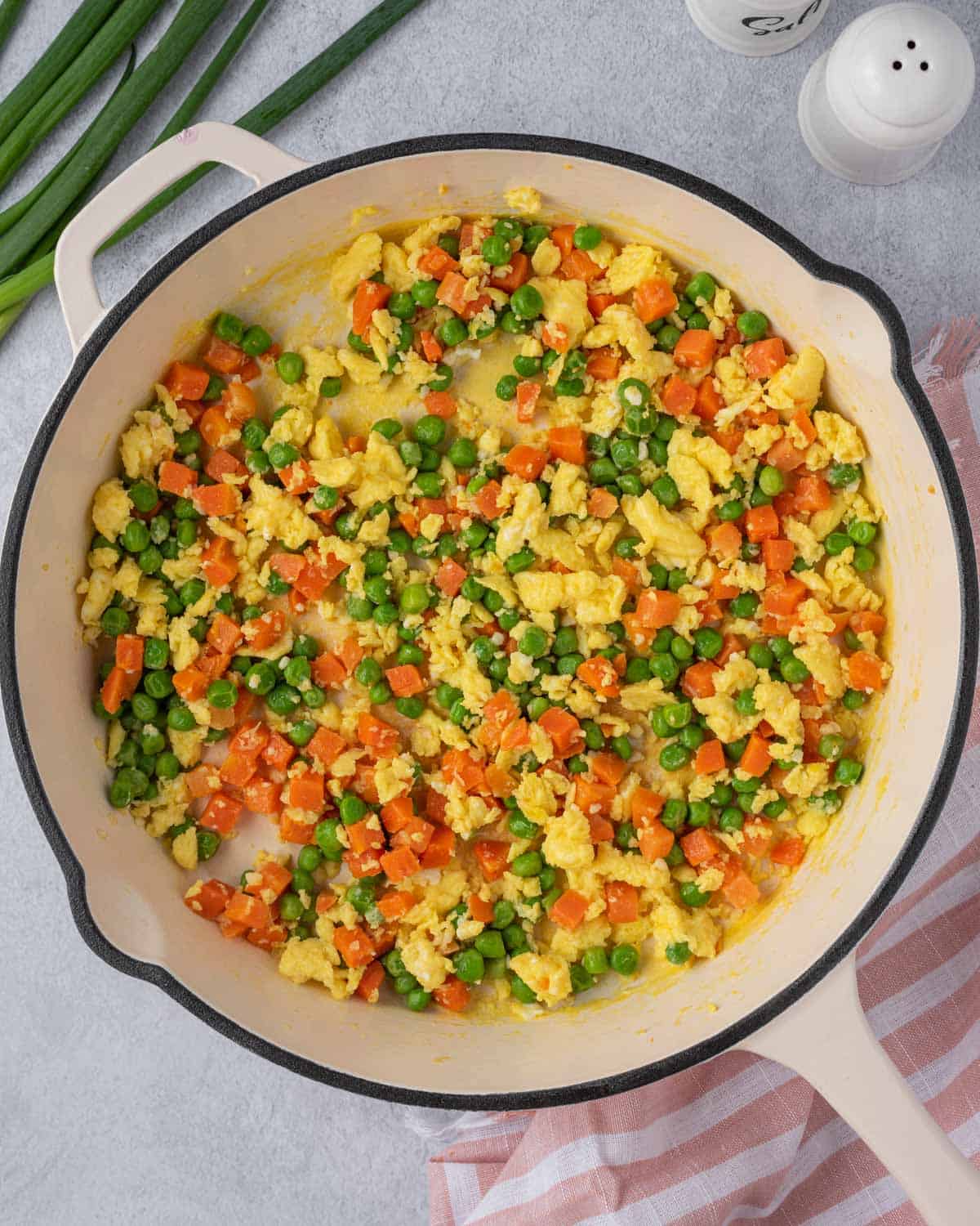 Eggs mixed with vegetables in a white pan.