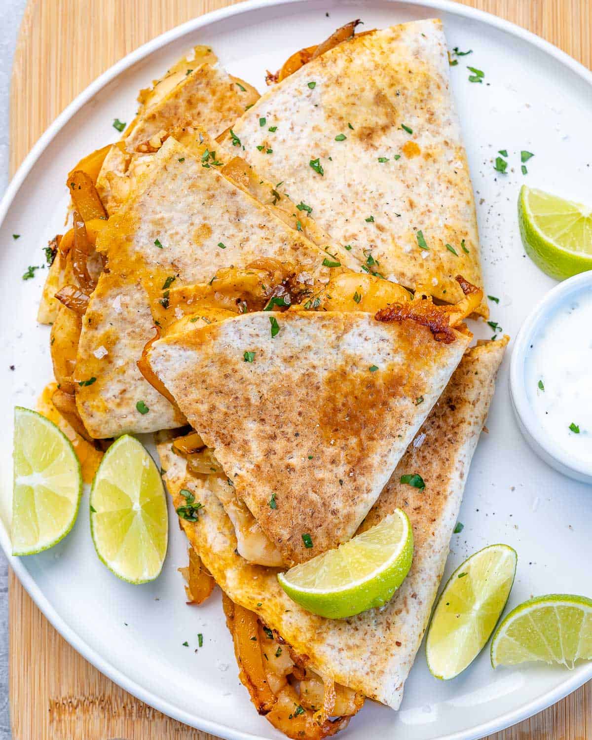 top view of shrimp quesadillas on white plate with limes 
