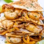 front view of shrimp quesadillas with parsley and lime wedges