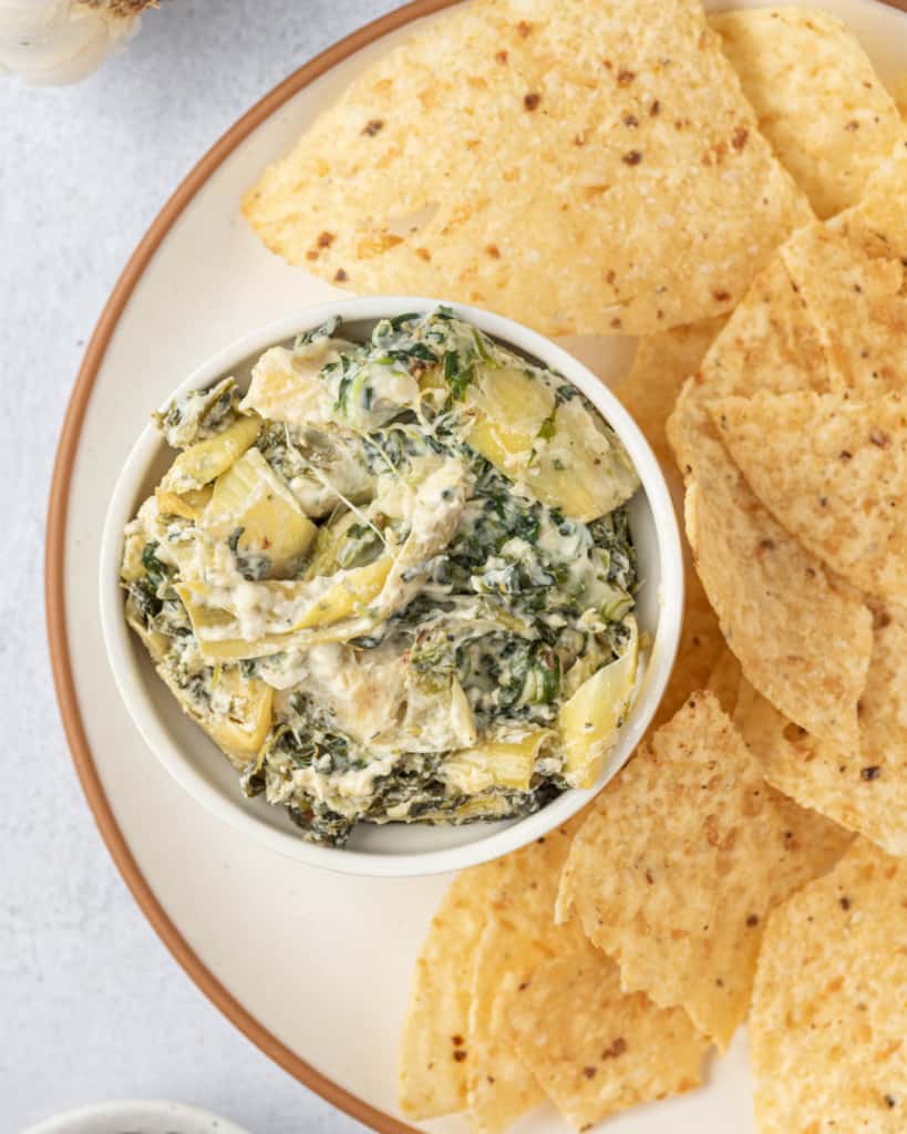 top view of artichoke dip in a small bowl served with tortilla chips 