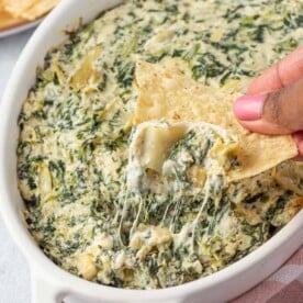 side shot of hand hold chips grabbing a bite of spinach dip