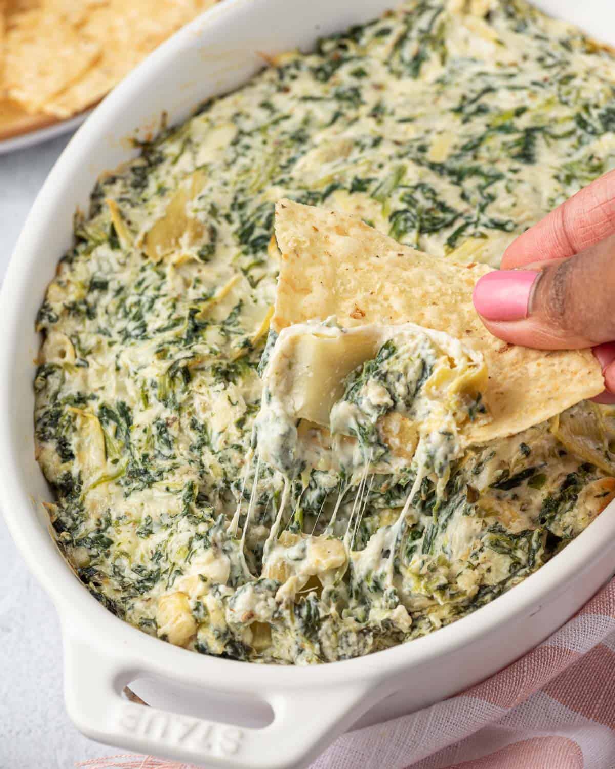 side shot of hand hold chips grabbing a bite of spinach dip