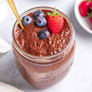 top view of chocolate chia pudding in a jar topped with blueberries and strawberries