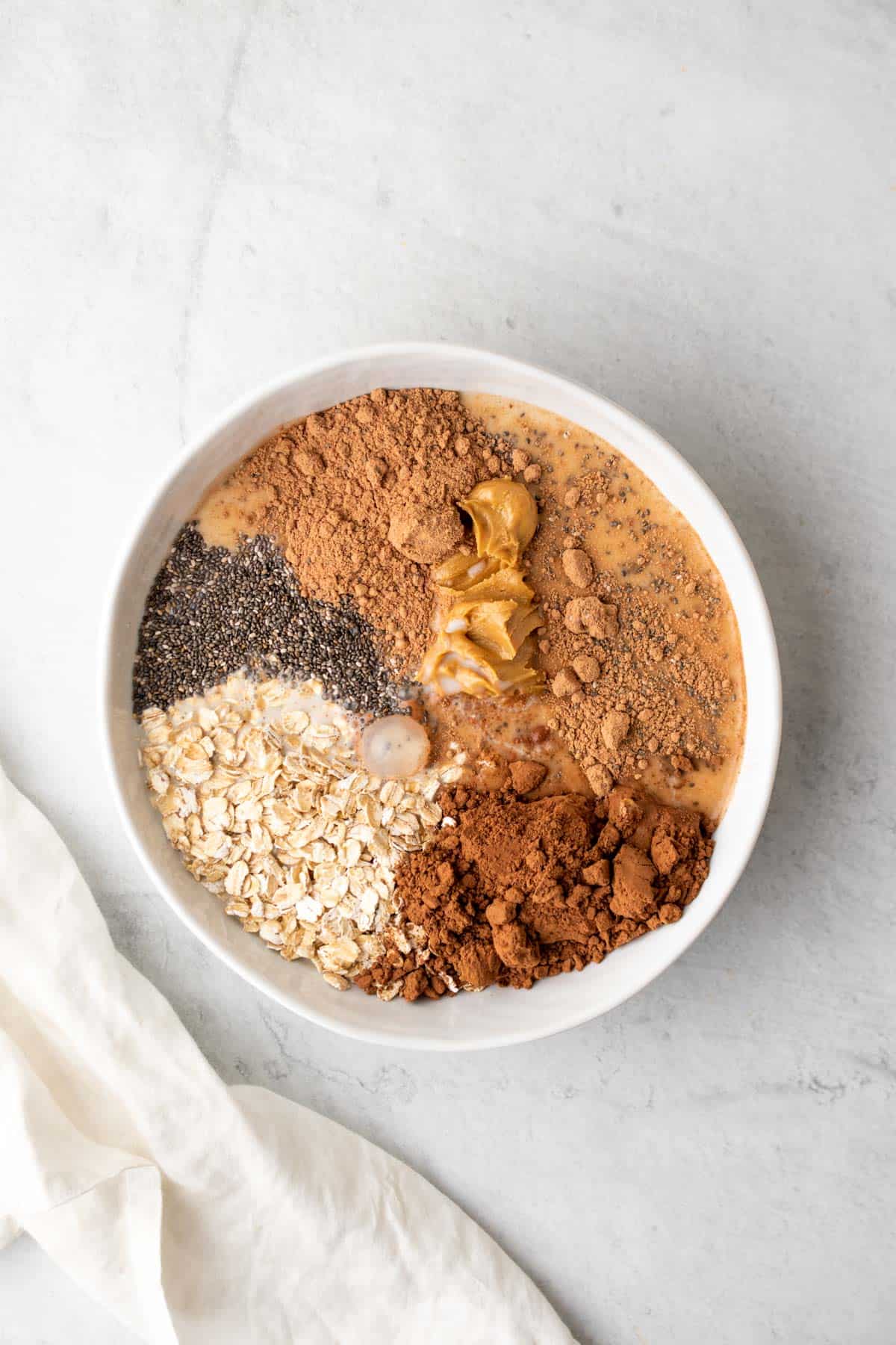 protein powder added to bowl of chocolate overnight oats ingredients