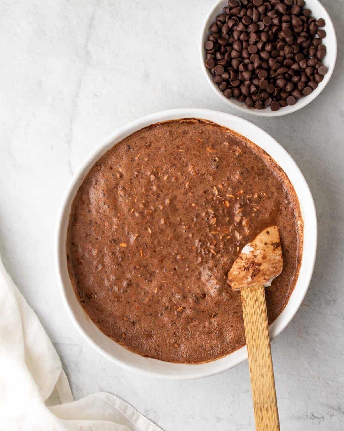 mixing oats with a spoon in a bowl with chocolate chips.