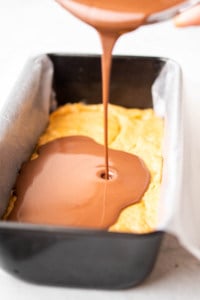 chocolate layer being poured over the peanut butter mixture in a pan