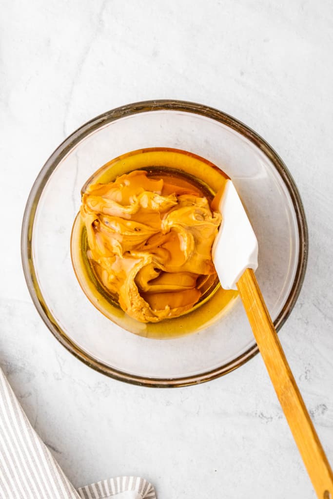 Peanut butter mixture in a clear bowl with a spatula.