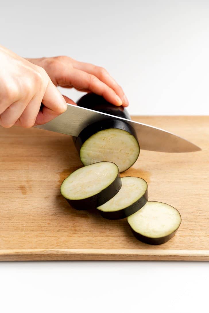 slicing an eggplant into rounds with knife