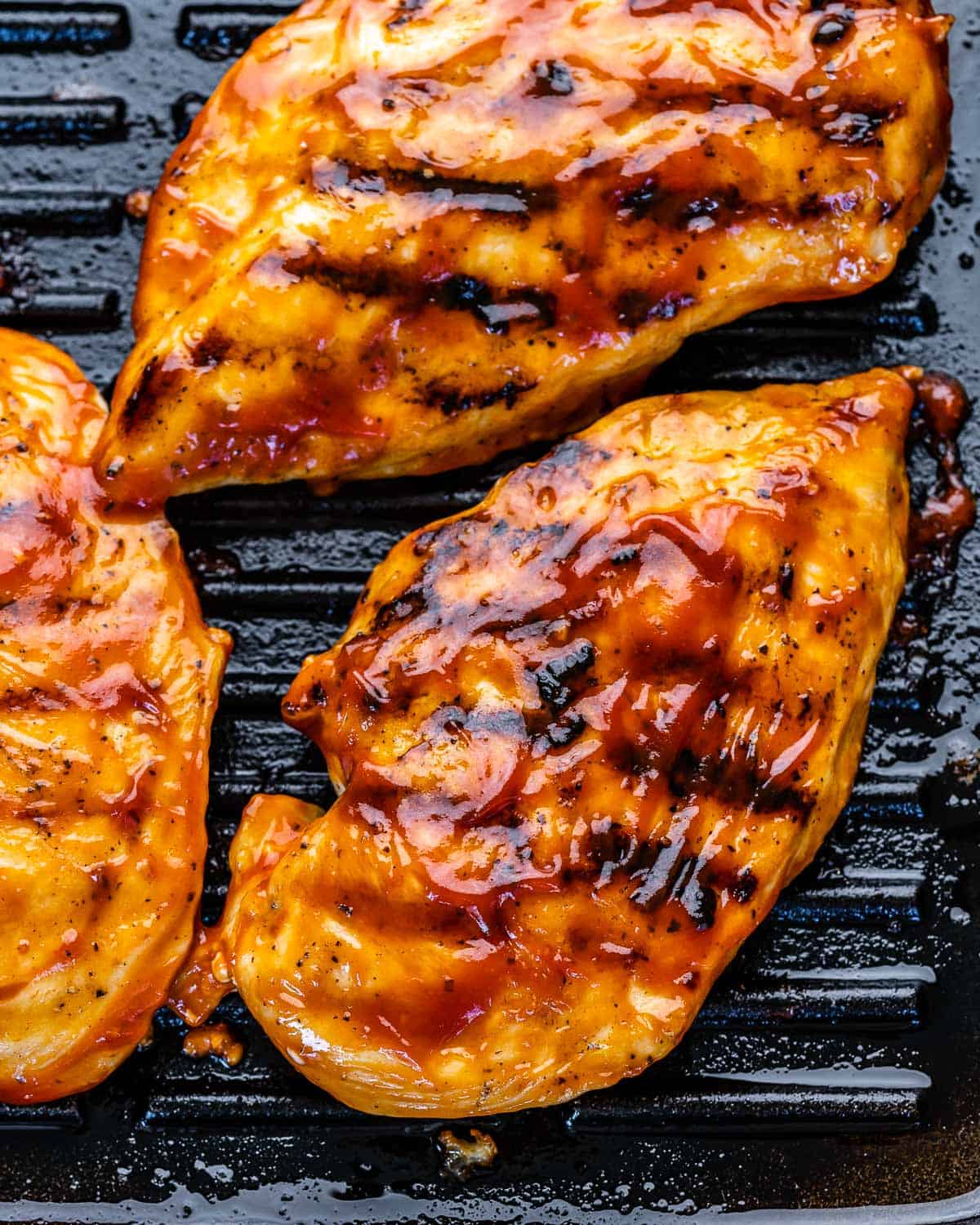 top view of chicken breasts on grill pan with BBQ sauce