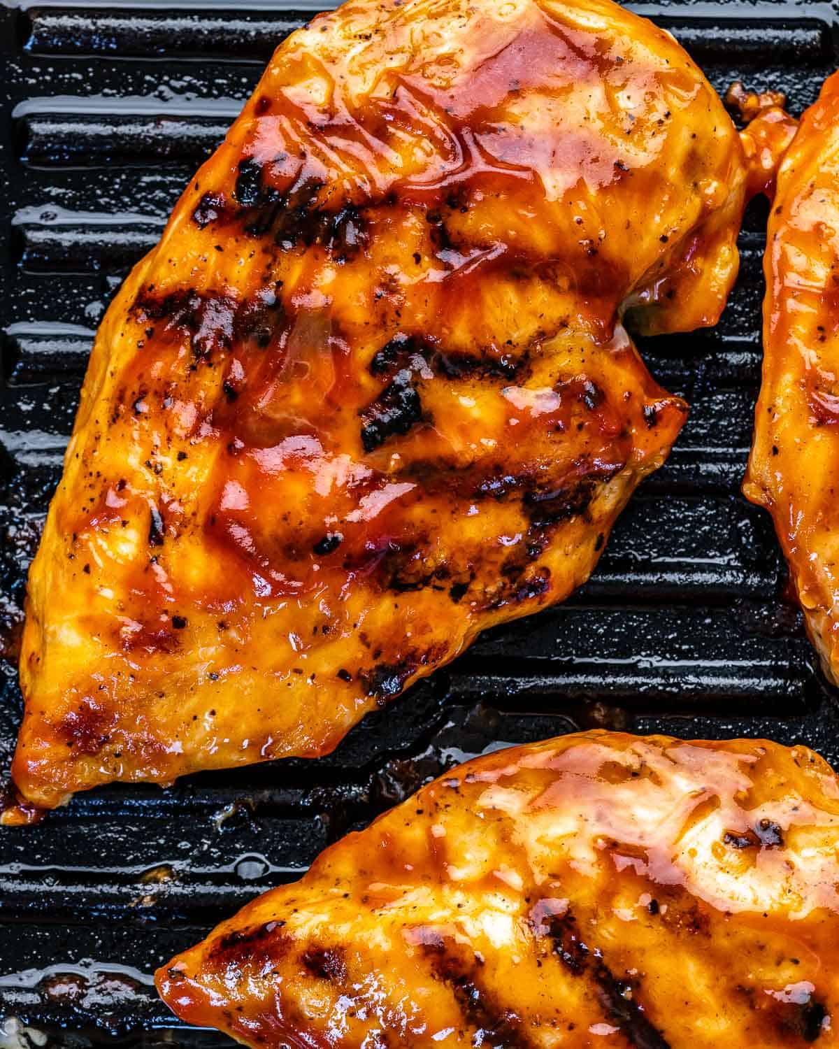 barbecue sauce on chicken breasts on grill pan