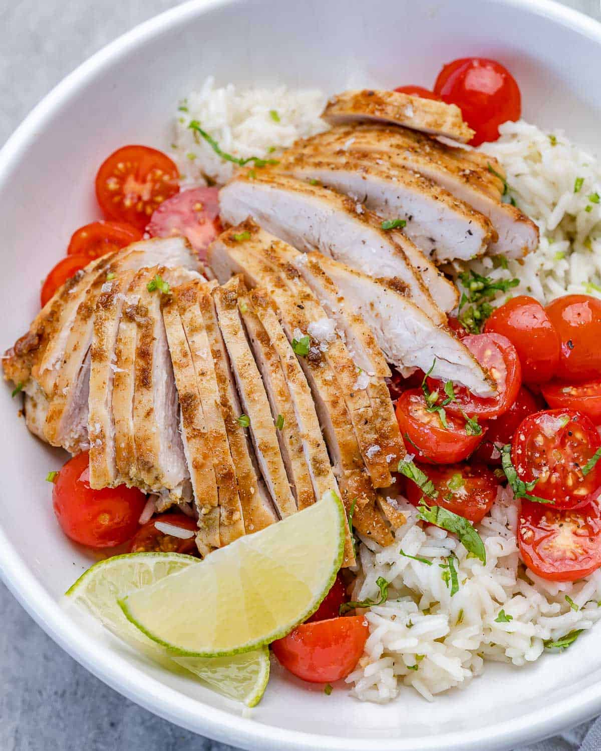 one bowl of cilantro lime chicken with rice, limes, and tomatoes