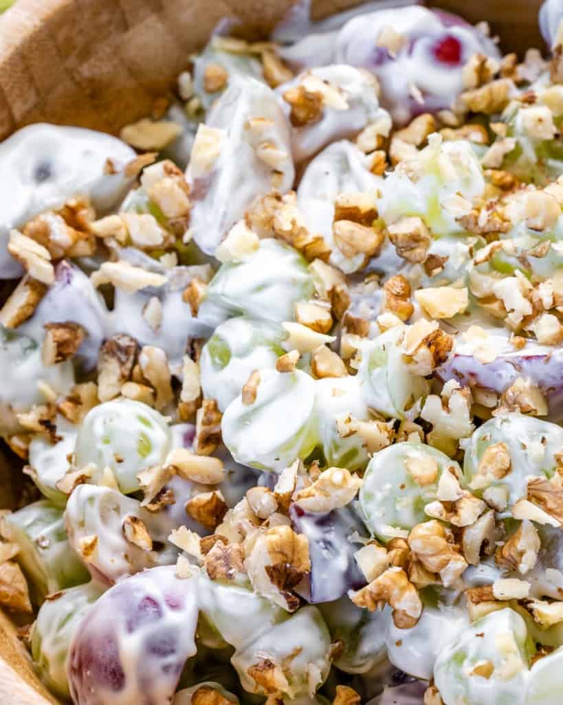 close up view of grape salad with yogurt and topped with crushed walnuts in a bowl