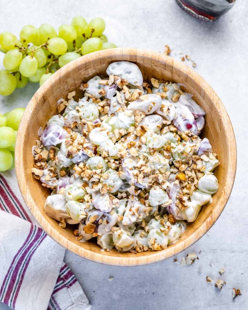 top view grape salad with yogurt topped with walnuts in a brown bowl