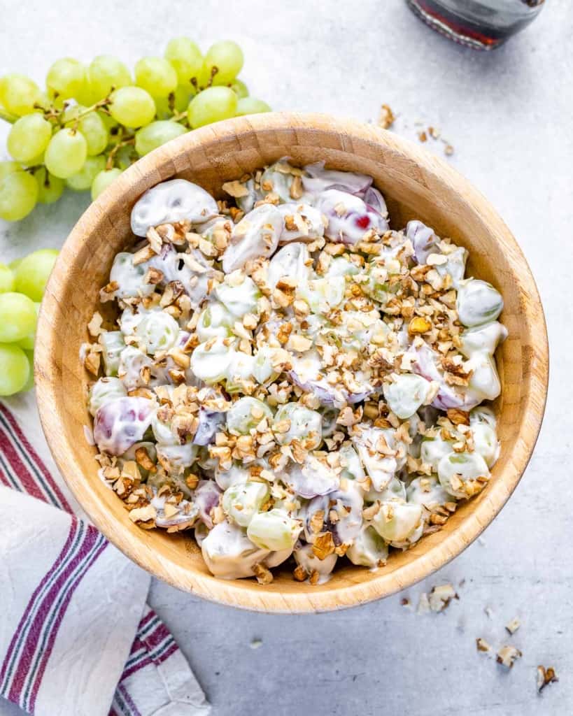 top view grape salad with yogurt topped with walnuts in a brown bowl