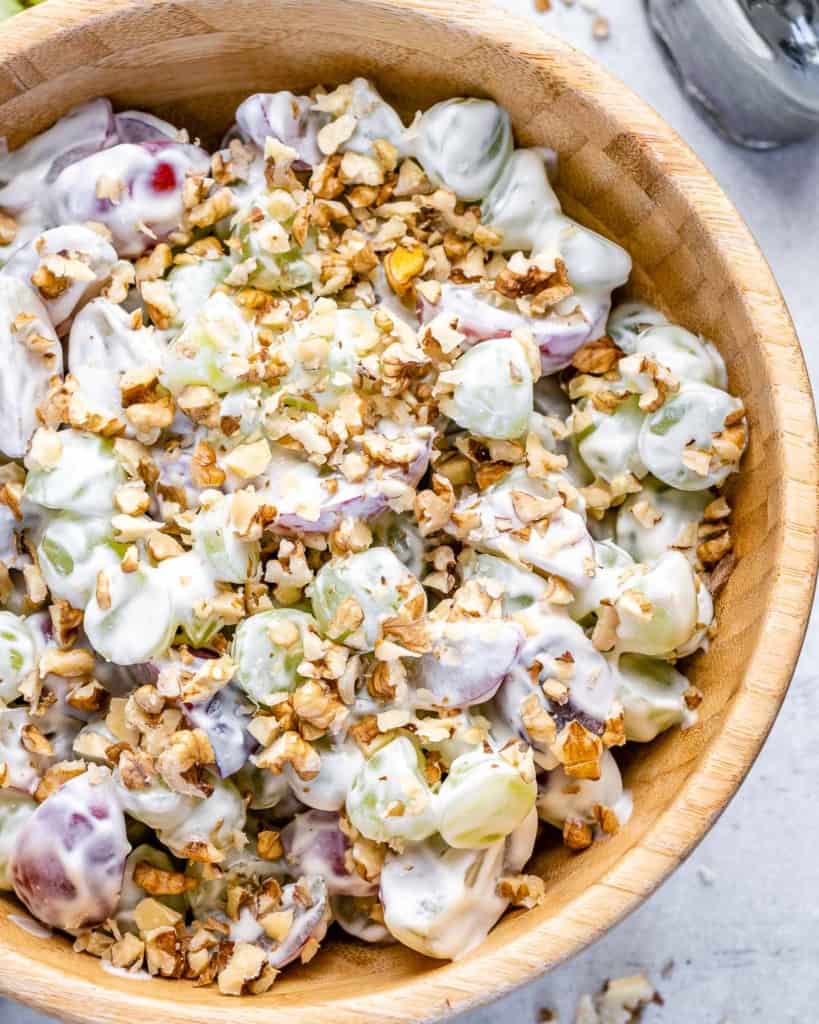close up top view grape salad with yogurt topped with walnuts in a brown bowl