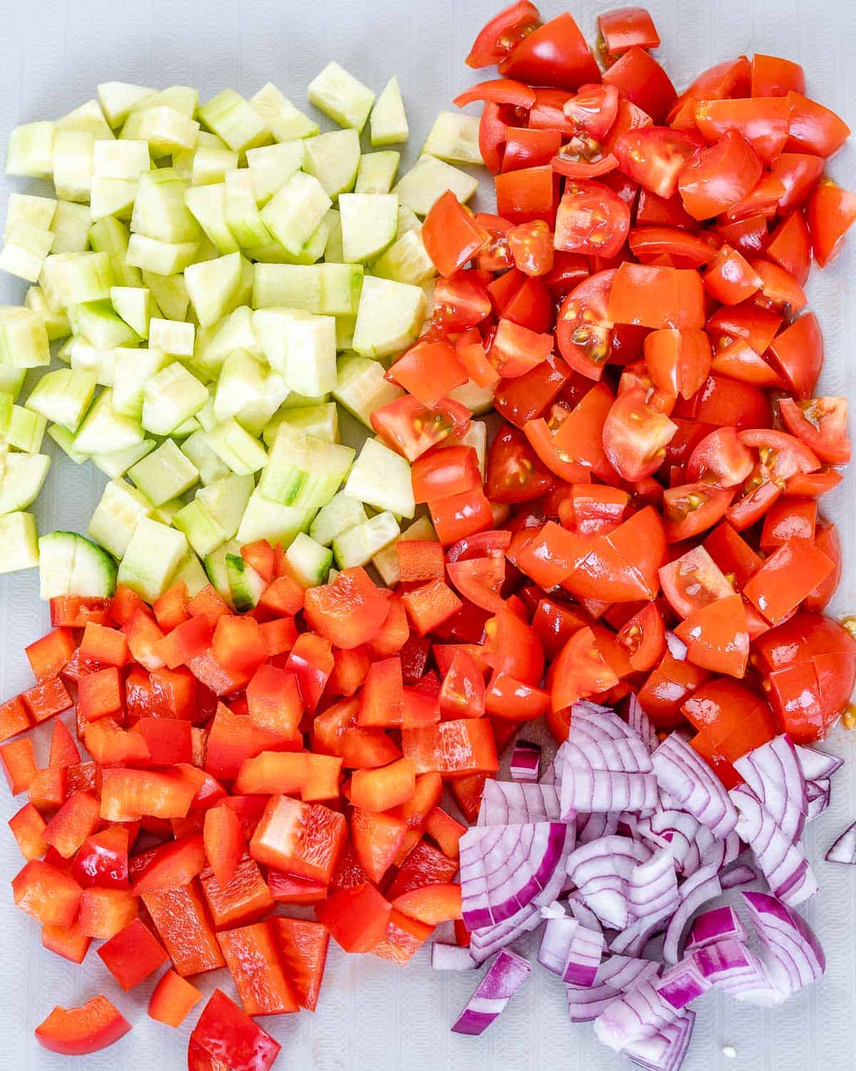 chopped red onions, tomatoes, cucumbers on cutting board