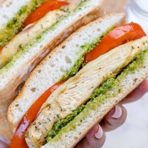 hand holding sliced grilled chicken sandwich