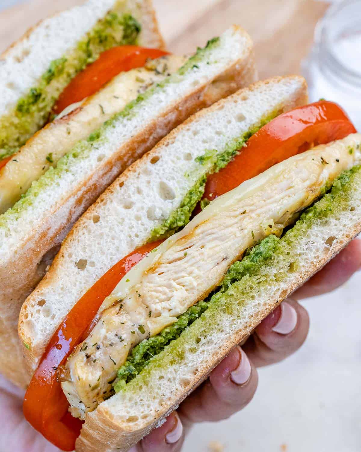 hand holding sliced grilled chicken sandwich
