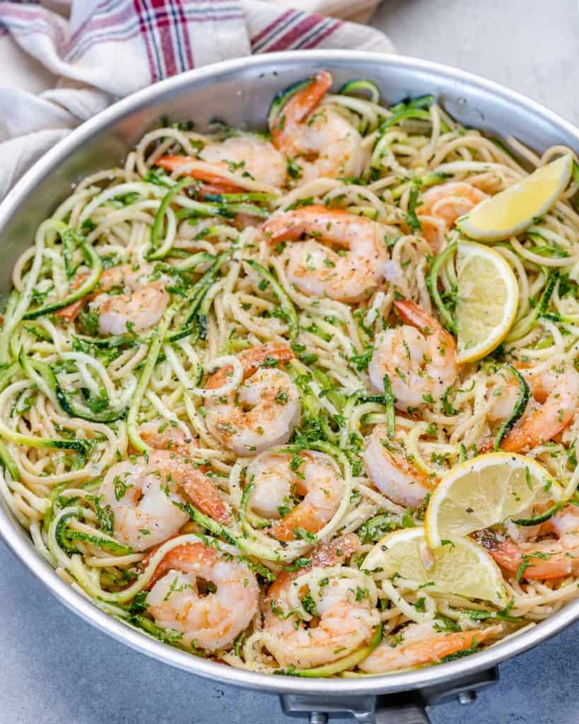 lemon garlic shrimp pasta in pan with zoodles and lemon wedges