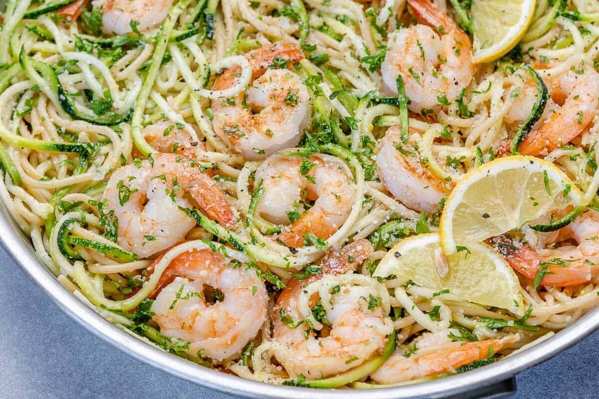lemon garlic shrimp pasta in pan with zoodles and lemon wedges