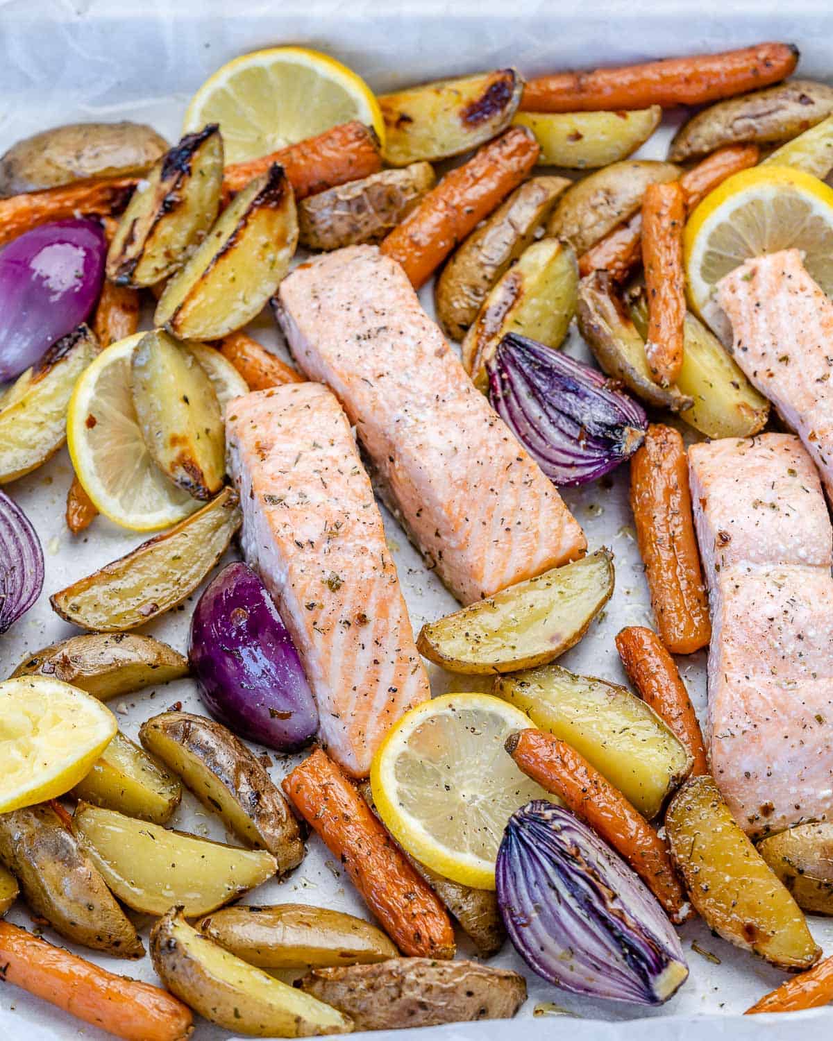 top view of oven-roasted salmon with potatoes and veggies on baking tray