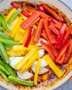 sliced peppers and onions on a skillet to be cooked for steak fajitas