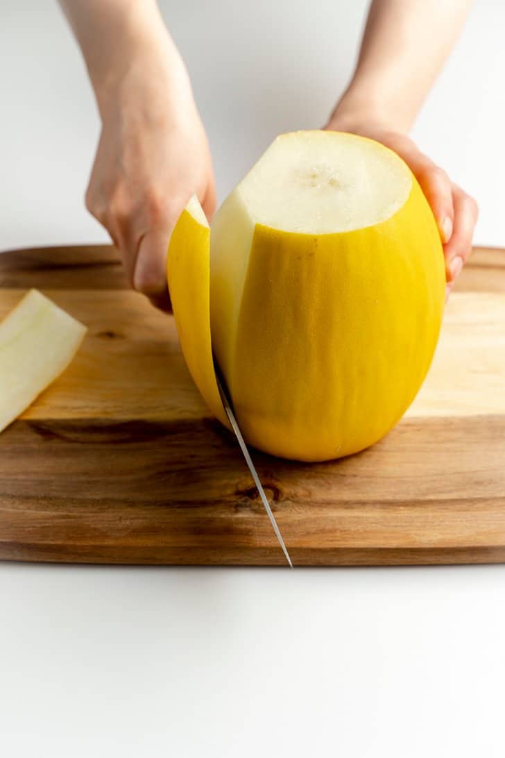 cutting the peel off a cantaloupe with knife
