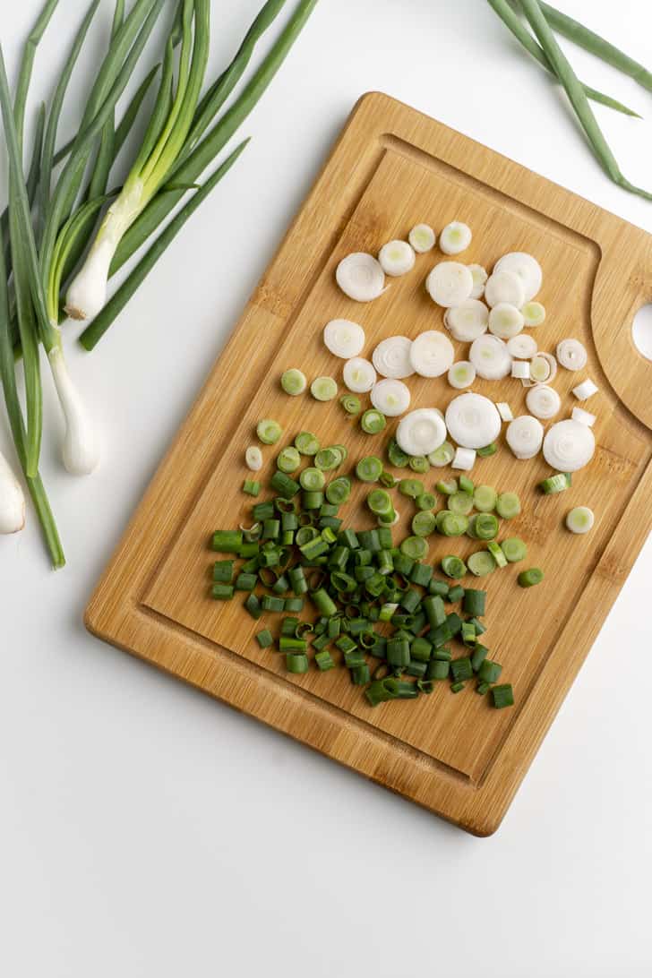 sliced green onions on wooden cutting board