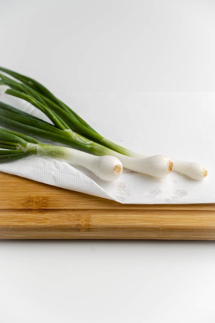 three onions on a cutting board with paper towel