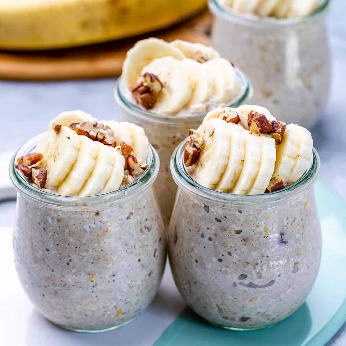 side shot of 3 jars of overnight oats topped with sliced bananas and walnuts