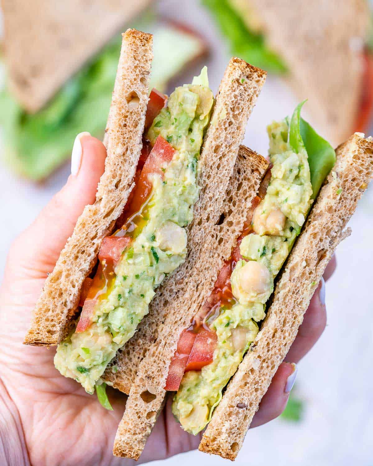 top view of avocado chickpea sandwich with tomato on bread slices