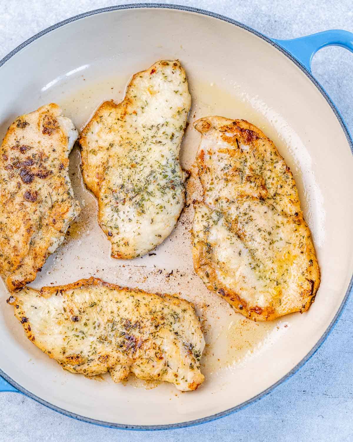 chicken cutlets in skillet with seasoning