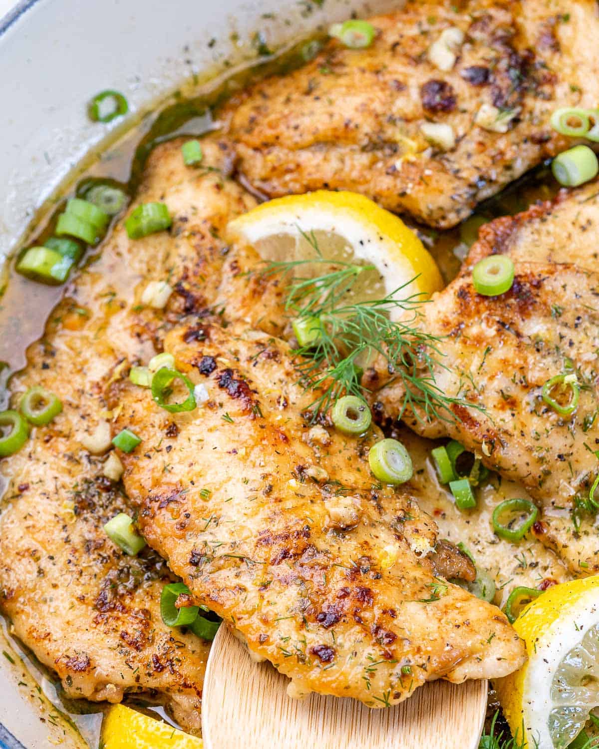 lemon chicken breast recipe in skillet with fresh dill and green onions