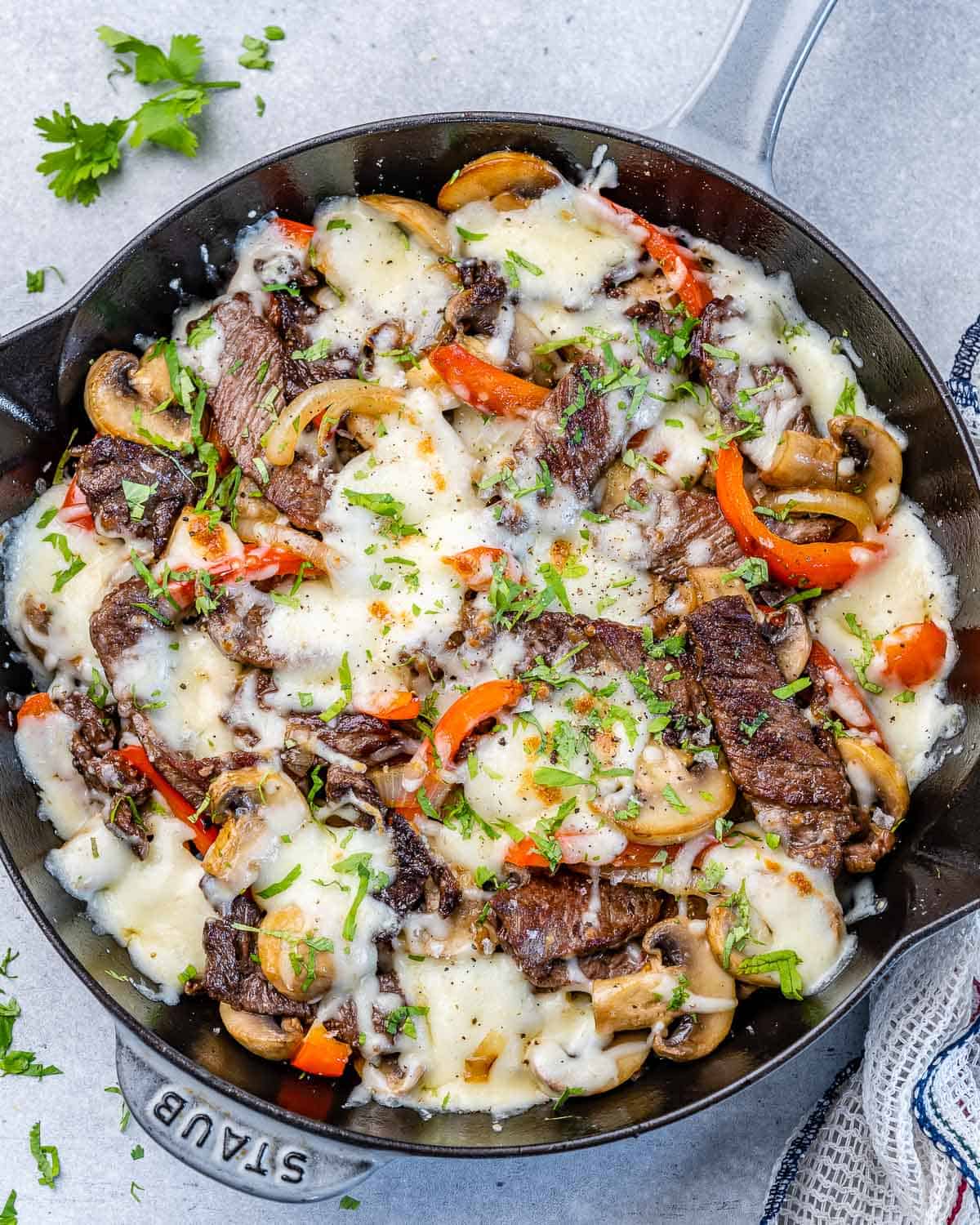 one skillet filled with philly cheese steak and melted cheese with veggies