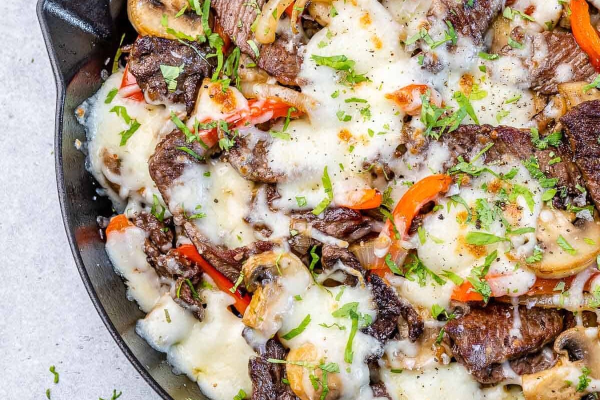 philly cheese steak recipe in skillet with veggies and melted cheese