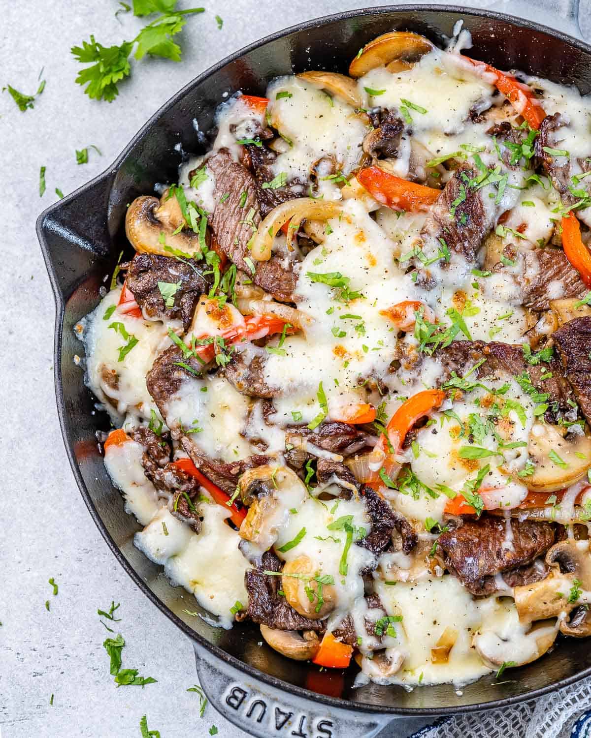 philly cheese steak recipe in skillet with veggies and melted cheese