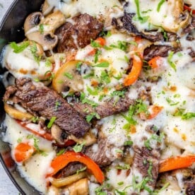 Philly cheese steak in pan with bell peppers, cheese, mushrooms, and cilantro