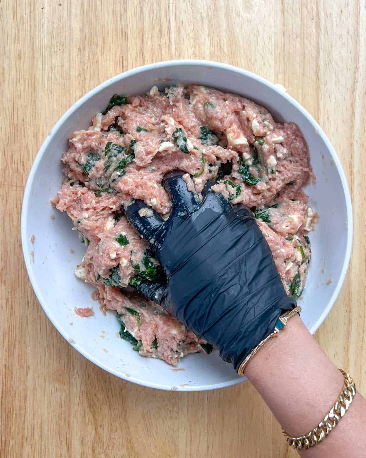 hand mixing all the burger ingredients in a bowl.