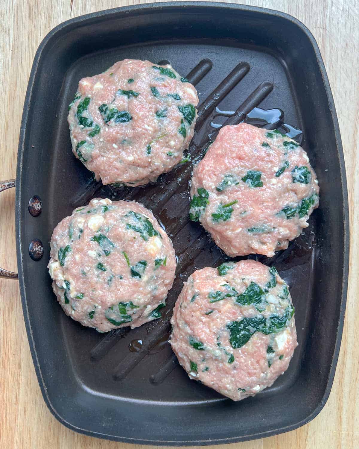 4 burger patties are placed on a pan before cooking.
