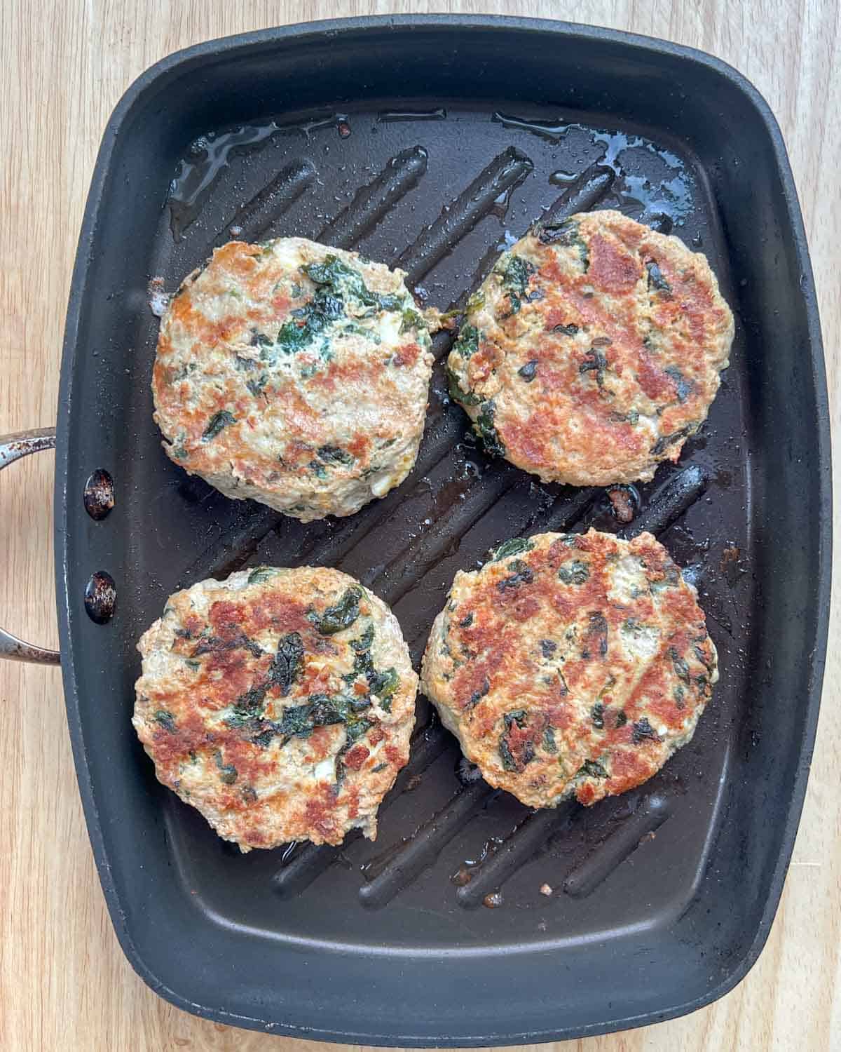 4 cooked burger patties on a pan.
