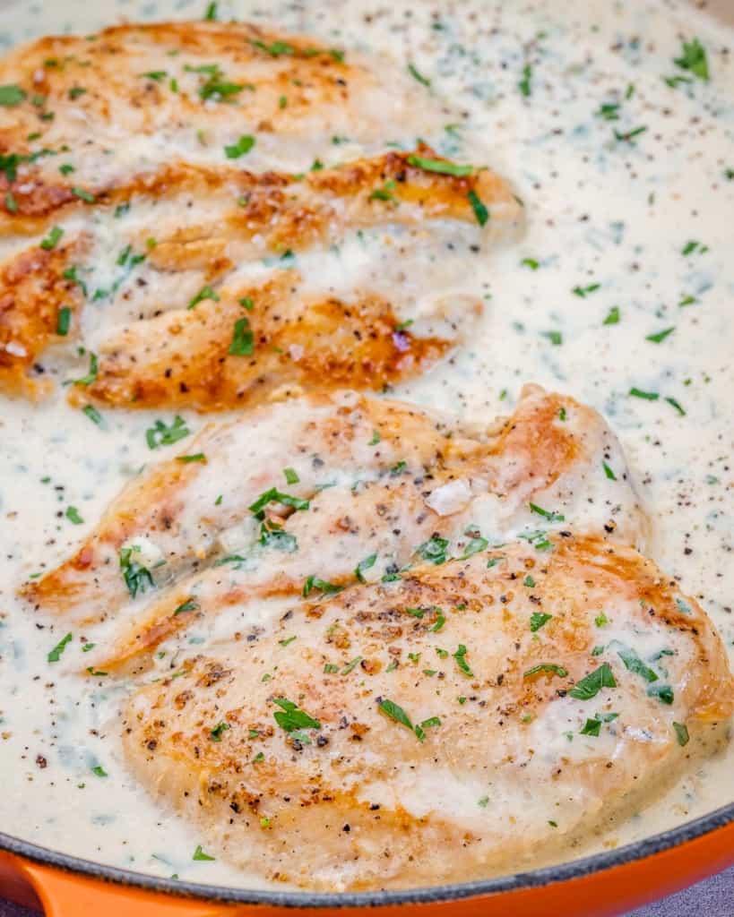 Chicken cooking in a cream-based sauce.
