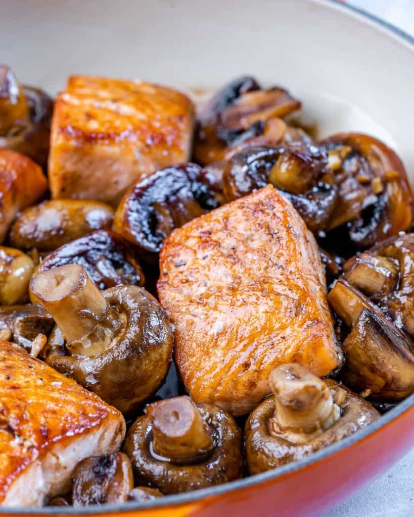 front view of salmon over mushrooms in skillet with balsamic honey glaze