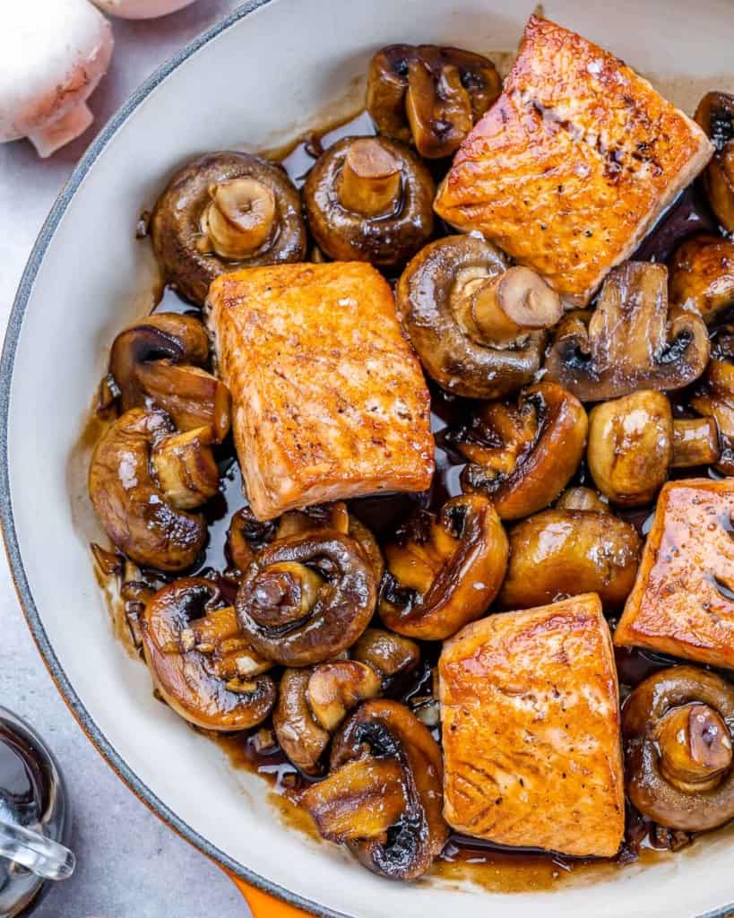 top view of salmon in skillet with mushrooms and honey balsamic glaze
