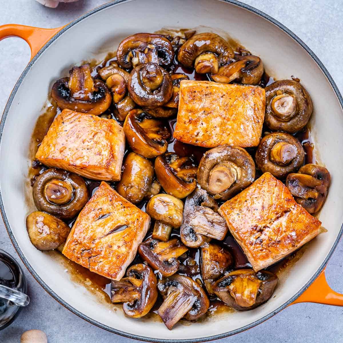 top view of pan seared salmon with mushrooms on an orange skillet
