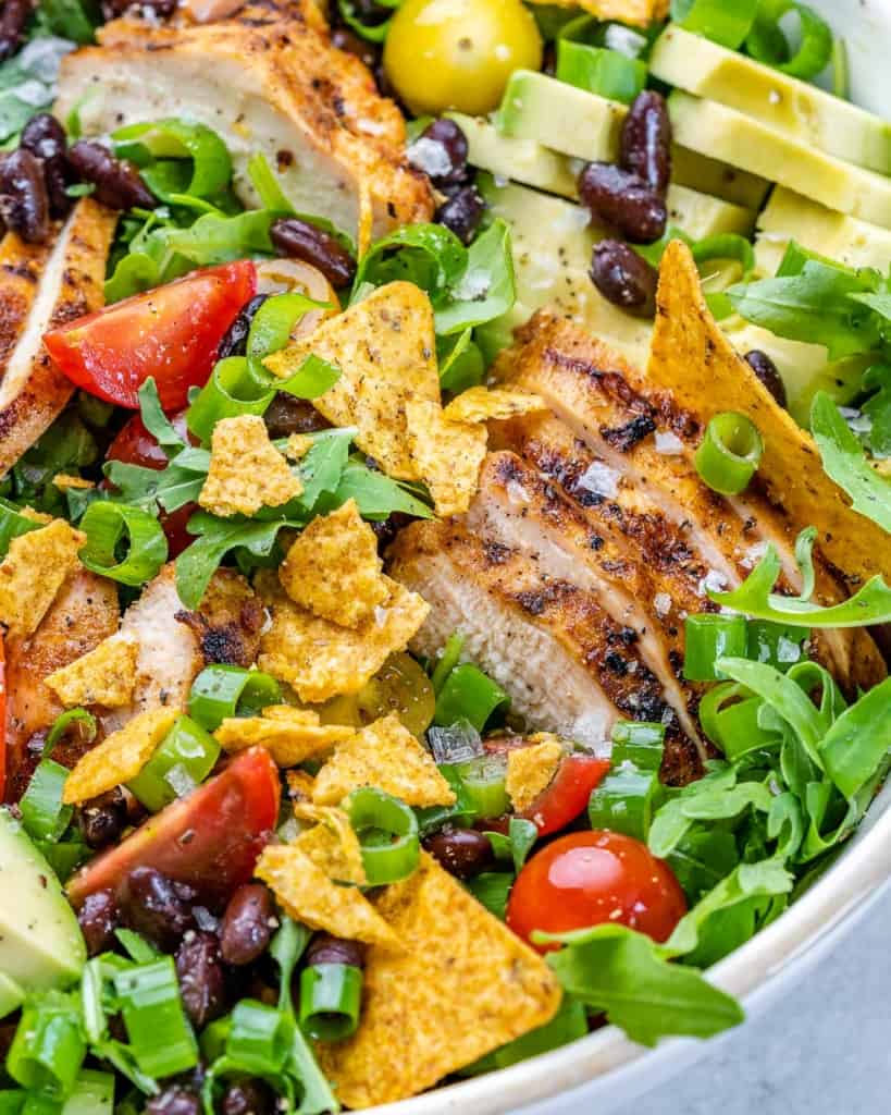 Close up of Santa Fe salad topped with sliced grilled chicken in a white bowl.