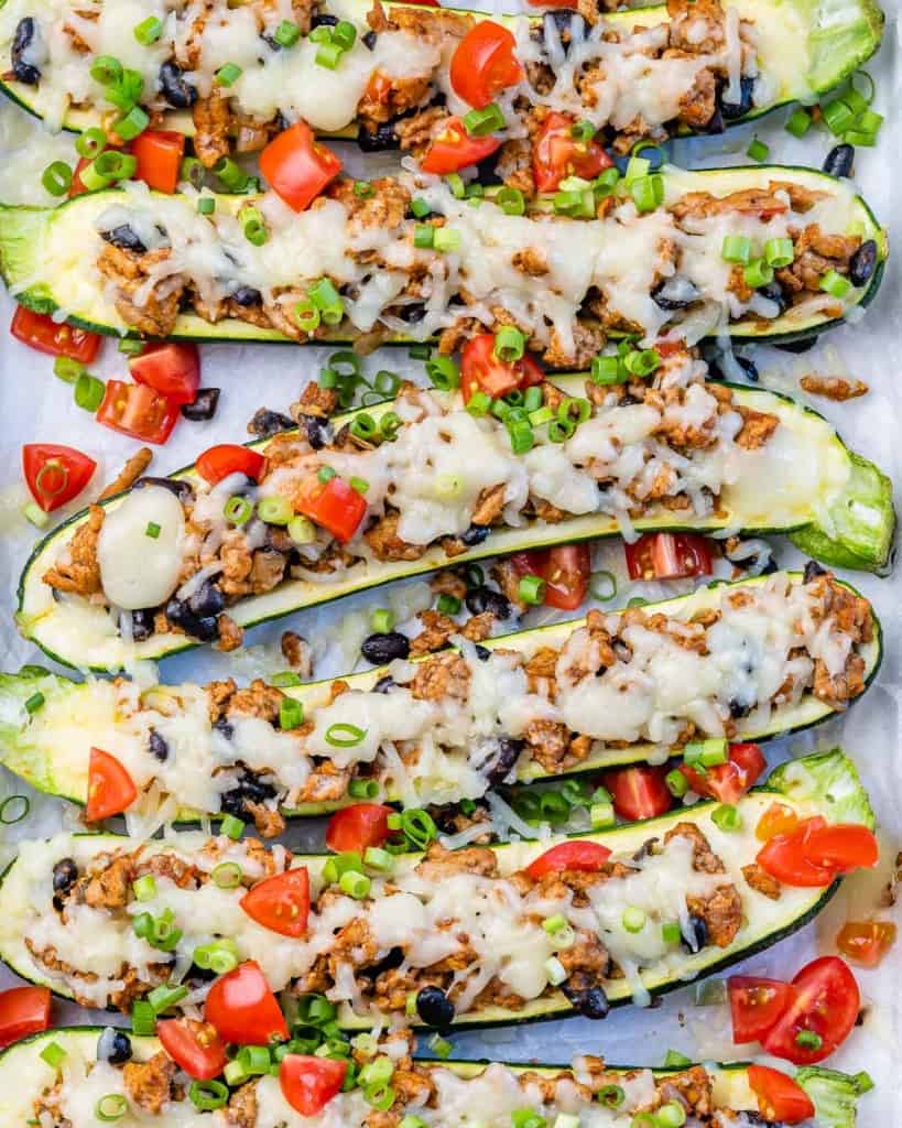 top view of stuffed zucchini boats with melted cheese and chopped tomatoes