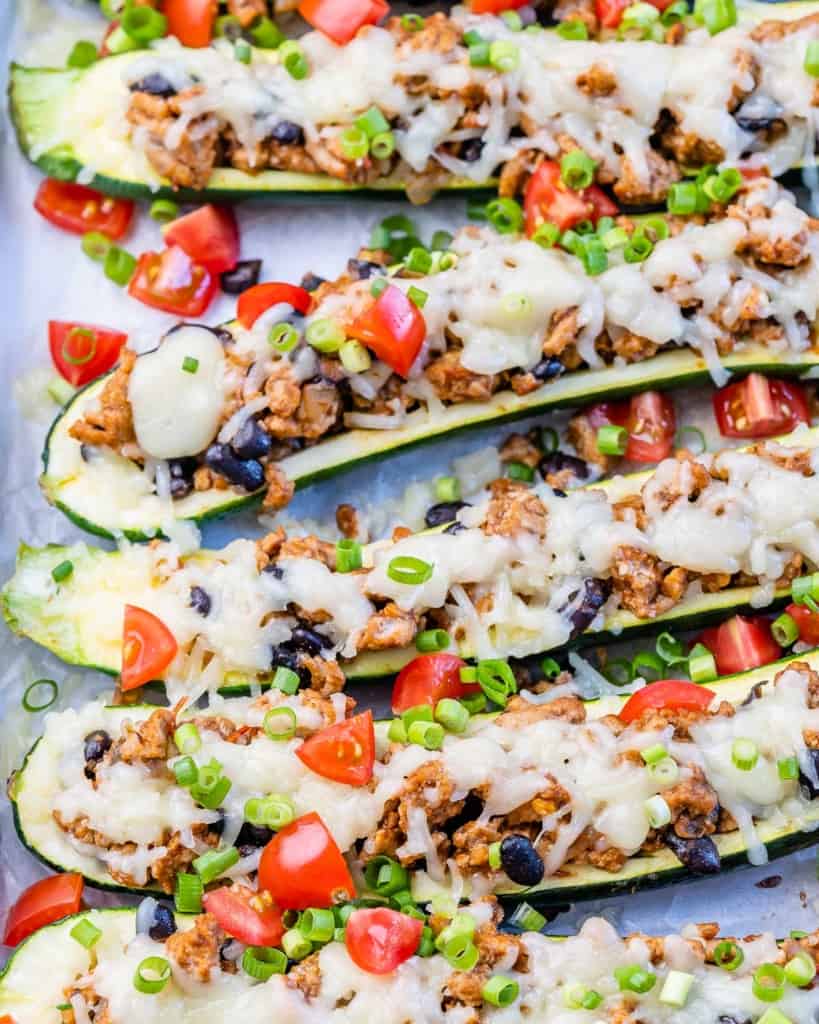 Top view of stuffed zucchini boats with melted cheese and chopped tomatoes